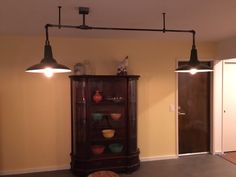 an empty room with two lights and a cabinet in the corner that has bowls on it