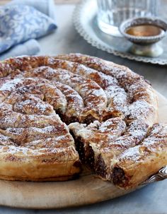 a pastry on a wooden board with one slice cut out