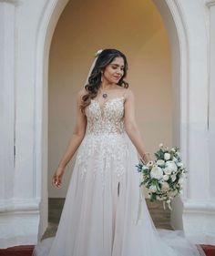 a woman in a wedding dress holding a bouquet and posing for the camera with her hand on her hip