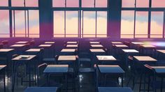 an empty classroom filled with desks and chairs in front of large windows at sunset