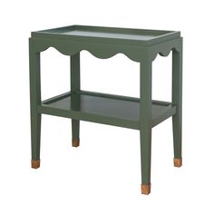 a green side table with wooden legs and an open shelf on the top, against a white background