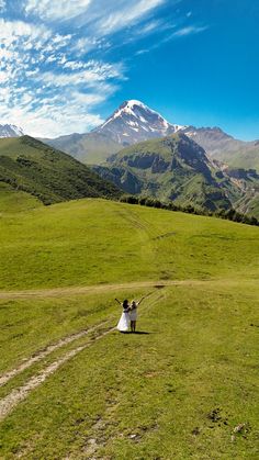 a bride and groom are walking in the mountains