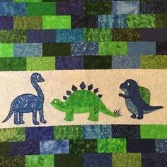 a quilted wall hanging with dinosaurs on it