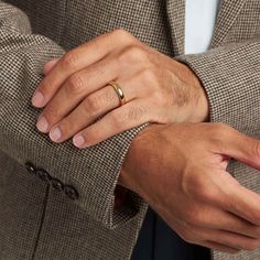 a man in a suit with his hands on his lapel wearing a wedding ring