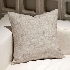 a pillow sitting on top of a white couch next to a wall with niches