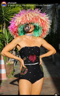 a woman in a black swimsuit with colorful decorations on her head and one hand on her hip