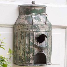 an old metal birdhouse hanging on the side of a door with a potted plant next to it