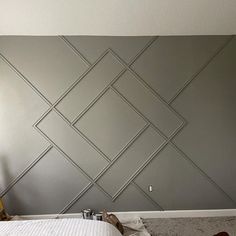 a bed sitting in a bedroom next to a wall with geometric designs on it's sides