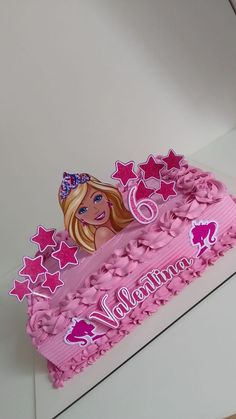 a pink birthday cake with a barbie doll on it's top and stars around the edges