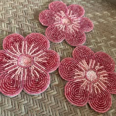 three red flowers sitting on top of a woven mat