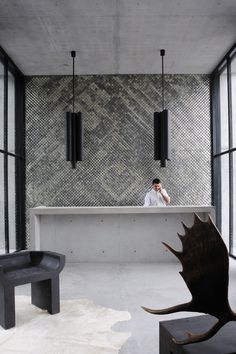 a person sitting at a counter in a room with large windows and black benches on the floor