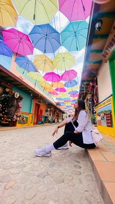 a woman sitting on the ground under umbrellas