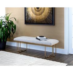 a white bench sitting next to a potted plant on top of a hard wood floor