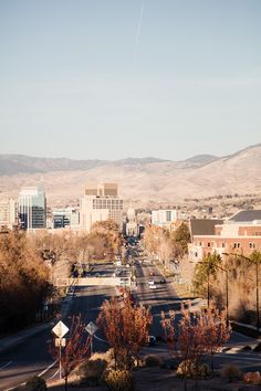 a city with mountains in the background and cars driving down the road on both sides