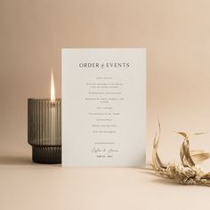 an order card next to a candle and some dried flowers on a table with a beige background