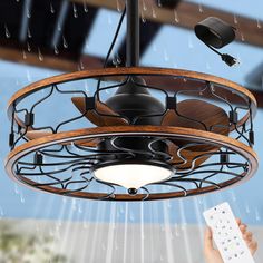 a person holding a remote control under a ceiling fan with rain coming down on it