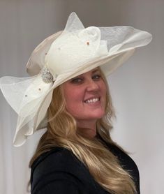 This is a beautiful neutral beige colored sheet hat. This stunning large brimmed hat does have an adjustable string on the inside, so this hat is one size fits all. There is a large sheer bow with gorgeous crystals all over it and clustered in the center. This is a gorgeous, elegant hat. Elegant Cream Fedora Hat, Elegant Adjustable Hat With Bow, Elegant Beige Fedora Hat, Elegant Brimmed Sun Hat With Bow, Elegant Beige Fedora Sun Hat, Chic Beige Hat With Bow, Elegant Fedora Sun Hat With Bow, Adjustable Cream Hat For Evening, Elegant Hat With Bow And Curved Brim