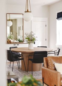 a dining room table with black chairs and a mirror above it, in front of a couch