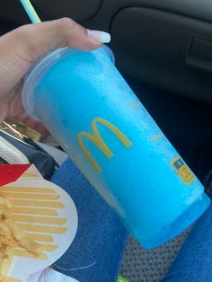 a person holding a blue cup with french fries on it and a drink in their hand