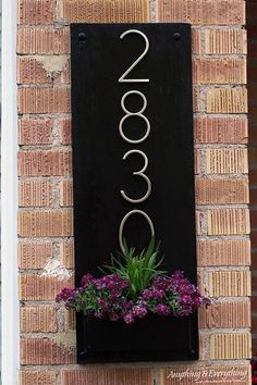 a black sign with the number 20000 on it and purple flowers in a window box