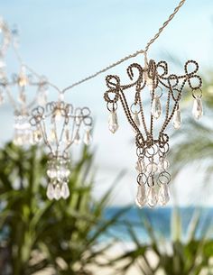 some kind of chandelier that is hanging from a wire near the beach and palm trees