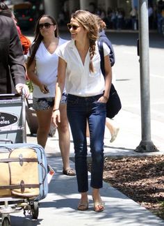 two women walking down the street with luggage