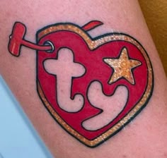 a heart shaped tattoo with the letter t in it's center and two stars on each side