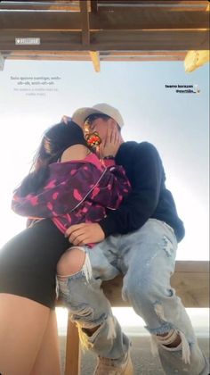 a man and woman sitting on top of each other in front of a wooden bench