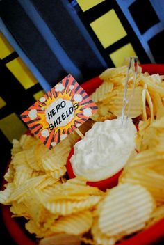 a red bowl filled with potato chips next to a small sign that says hero shields