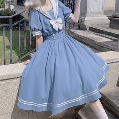 a woman wearing a blue dress and white shoes is posing on steps with her hand in the air