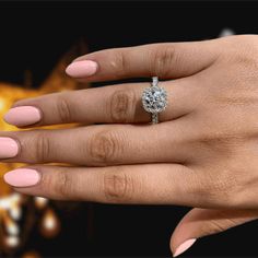 a woman's hand with pink manicured nails and a diamond ring