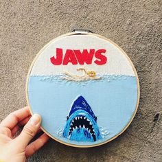 someone is holding up a hand embroidered picture of a shark with jawss on it