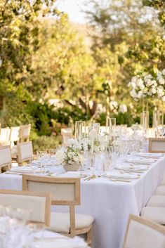 the table is set with white flowers and place settings