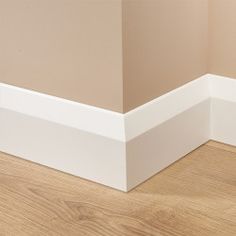 the corner of a room with wood flooring and white trim on the wall above it