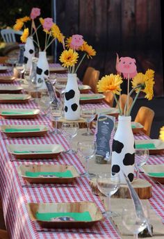 there are many vases with flowers in them sitting on the long table set for dinner