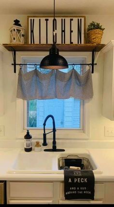 a kitchen sink under a window with a sign above it that says kitchen and a sink