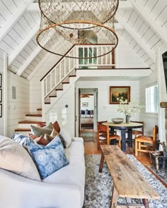 a living room filled with furniture and a chandelier hanging from the ceiling over a wooden table