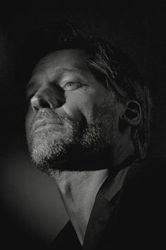 a black and white photo of a man looking up at something in the air with his eyes closed