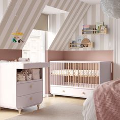 a baby's room with pink and white stripes on the walls, dressers and crib