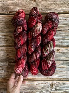 hand - dyed yarn skeins in shades of red, brown and beige on wooden background