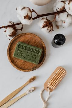 a wooden brush, comb and soap sitting on a table next to cotton floss