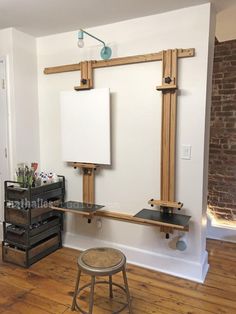 an empty room with two easels, a stool and a white board on the wall