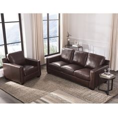 two brown leather couches sitting on top of a rug in front of a window