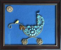 a baby carriage made out of beads and bead on a blue background in a framed wooden frame