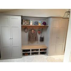 a room with some gray cupboards and white walls, one has a coat rack on the other side