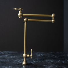 an old fashioned brass faucet on a marble countertop with black walls in the background