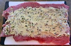 raw meat on a cutting board with seasoning and pepper sprinkled on top