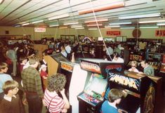 a group of people playing video games in a room filled with arcade machines and other items