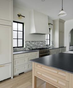 a large kitchen with white cabinets and black counter tops, along with an island in the middle