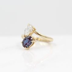 a yellow gold ring with two pear shaped diamonds and a blue sapphire in the center